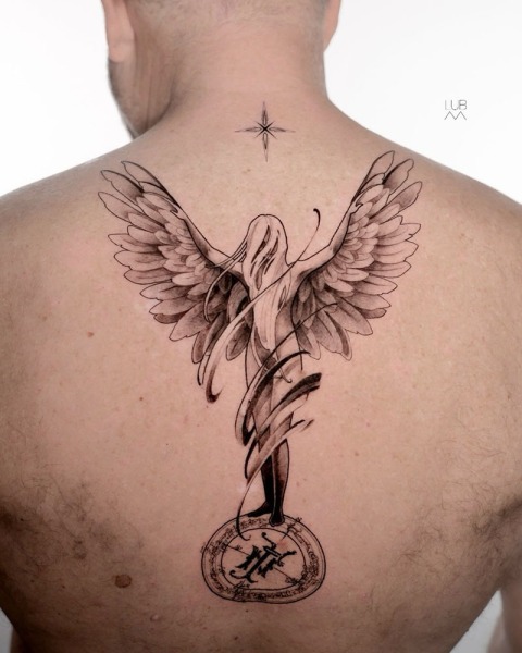 A divine vertical composition: This custom fine-line angel piece by Lubava blends celestial symbolism with sharp, technical linework on the upper back.