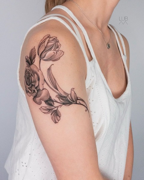 Botanical elegance: This custom-wrapped floral shoulder and upper arm piece by Lubava features intricate shading and soft-contrast realism
