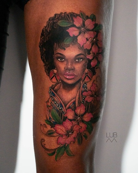 Portrait Perfection: This custom illustrative color piece by Lubava captures exquisite facial realism and vibrant botanical details on the thigh.